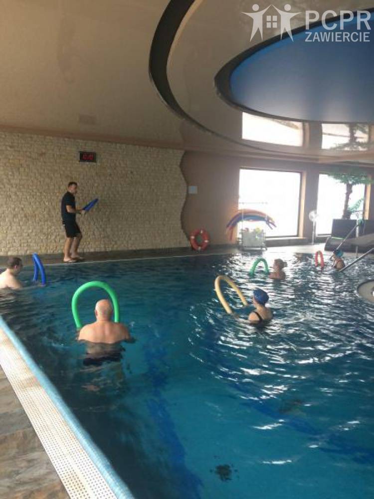 Zdjęcie: Grupa kobiet i mężczyzn w basenie wykonuje ćwiczenia z wykorzystaniem piankowych makaronów